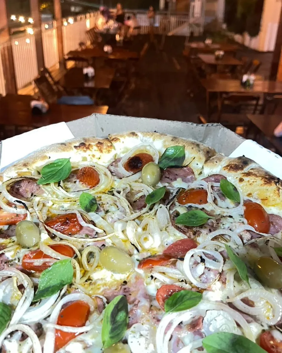 Pizza sendo aberta na caixa com o deck da Duu Horse iluminado ao fundo