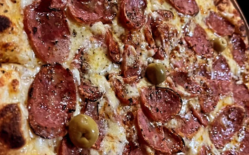Pizza de calabresa com azeitonas verdes recém-saída do forno