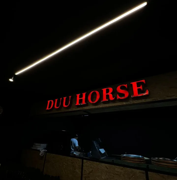 Letreiro neon vermelho 'Duu Horse' aceso à noite na fachada, no Centro de Cajati